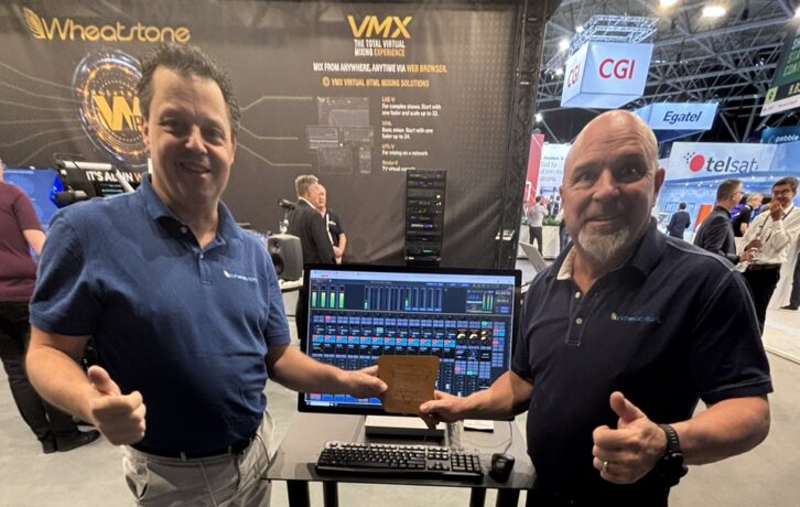 Two men stand in the Wheatstone booth at IBC 2026 with a computer screen and an award